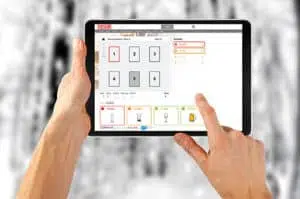 Intelligenter Bierdeckel SmartCall gewinnt German Innovation Award 2 Hand, die einen Computer und ein Tablet hält, Symbol für Technologie und Kommunikation, mit Schrift und Finger-Geste.